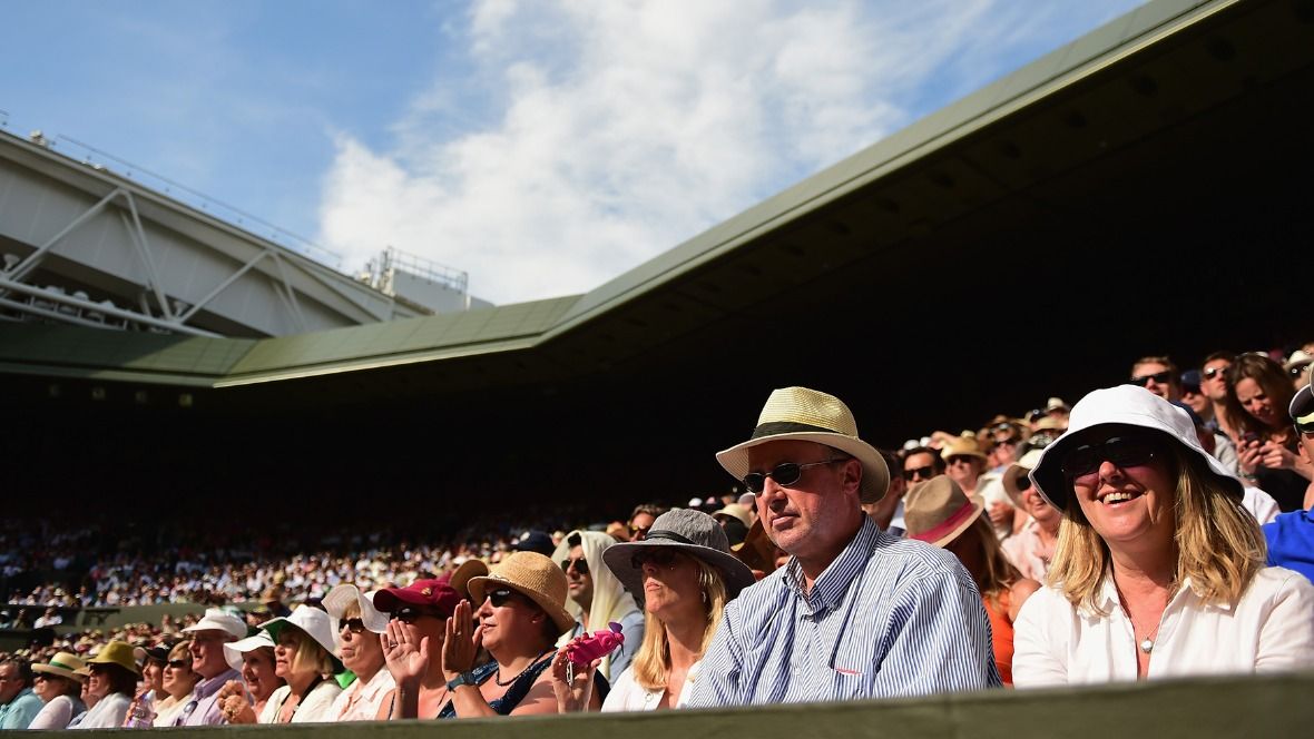 Wimbledon spectators wearing hats and sunglasses to shield themselves from the sun